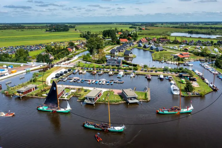 Nederland, De Veenhoop, 01-08-2022. SKS skûtsjes varen langs Vakantiepark Waterpark De Alde Feanen.